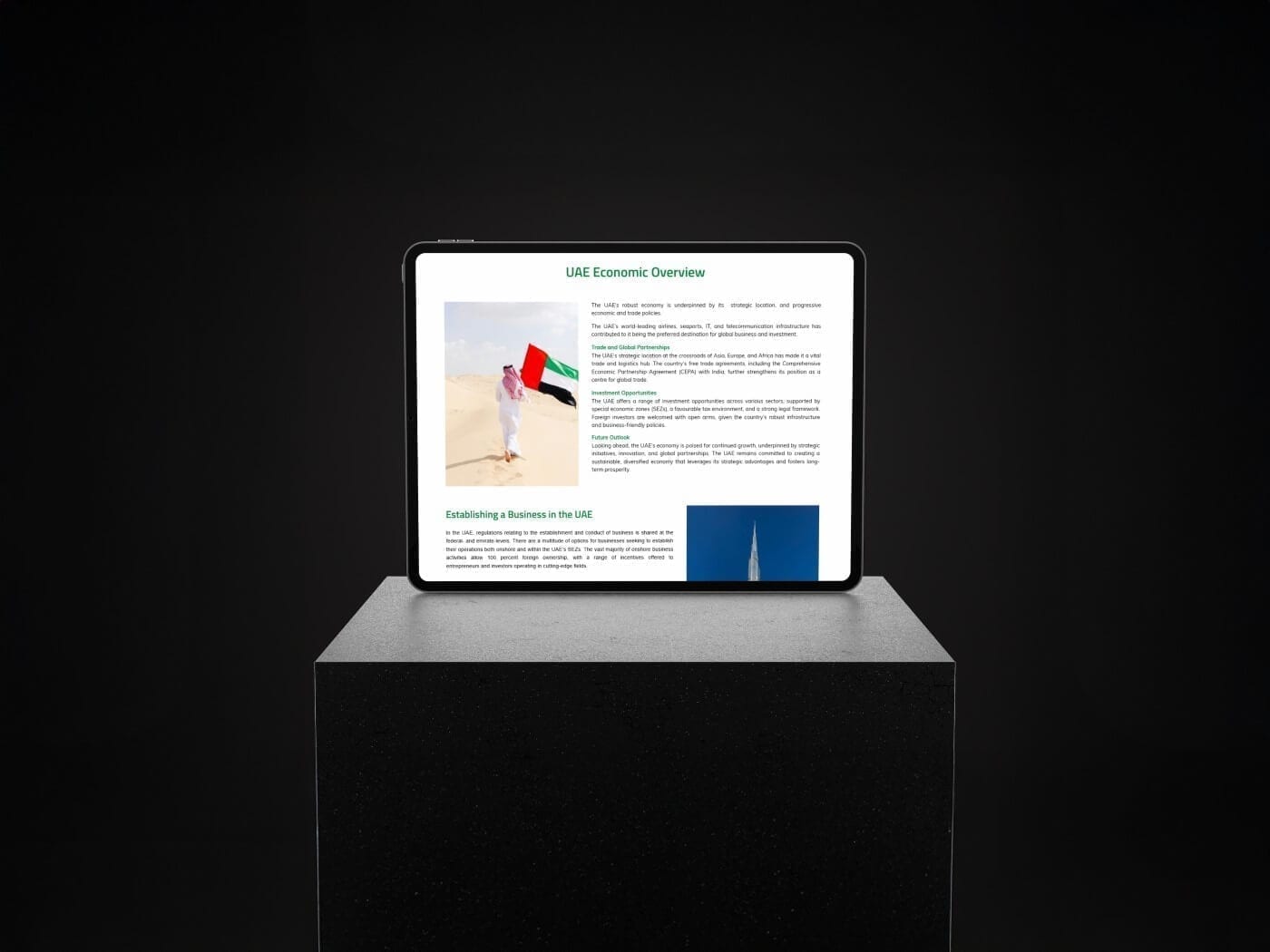A tablet on a black plinth showing the UAE Economic Overview page, with a photo of a person holding a UAE flag and an “Establishing a Business in the UAE” section.