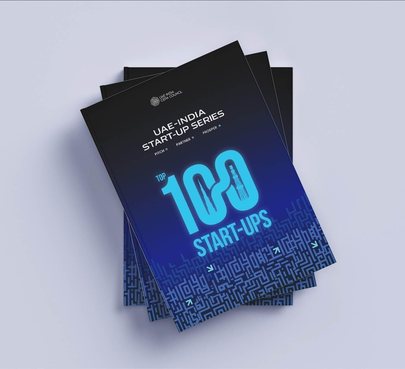 Top-down view of the dossier cover: “UAE–India Start-up Series, Top 100 Start-ups” in bright blue on a dark blue maze pattern.