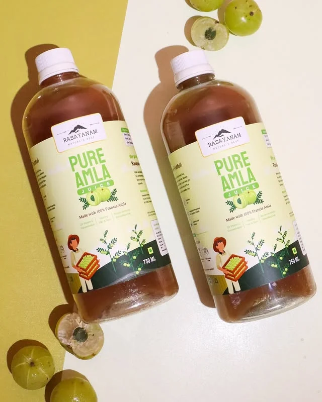 Two bottles of Pure Amla Juice against a yellow background, with amla fruit.