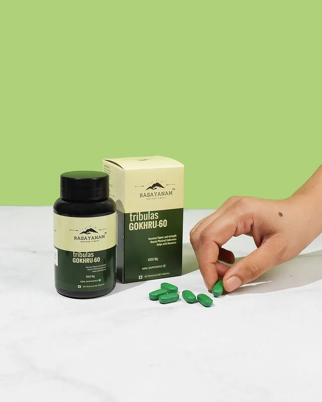 A hand picking up a green capsule beside a Rasayanam supplement bottle and box, on a green and white background.